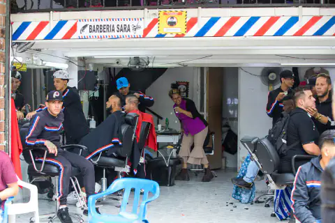 Barbería a pie de calle con clientes esperando en la puerta