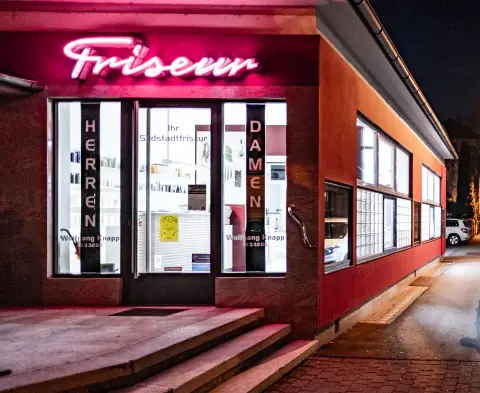 Fachada del local iluminada en rojo con el rótulo de neón