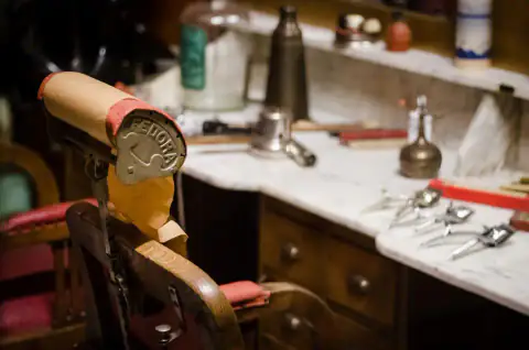 Tocador de mármol con las herramientas del barbero junto al sillón