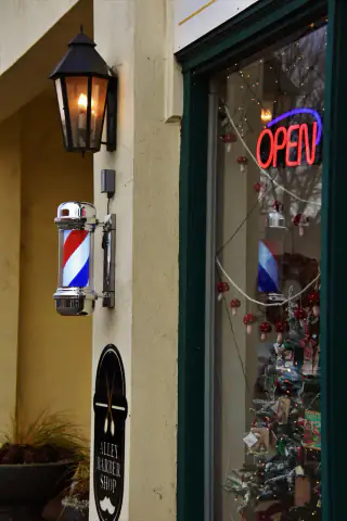 Poste de barbero y rótulo de abierto en la puerta del local