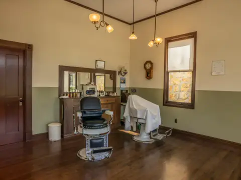 Salón clásico con sillón de barbero, espejo de madera y suelo entarimado