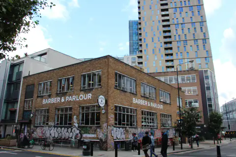 Edificio de ladrillo con el rótulo de la barbería en la esquina
